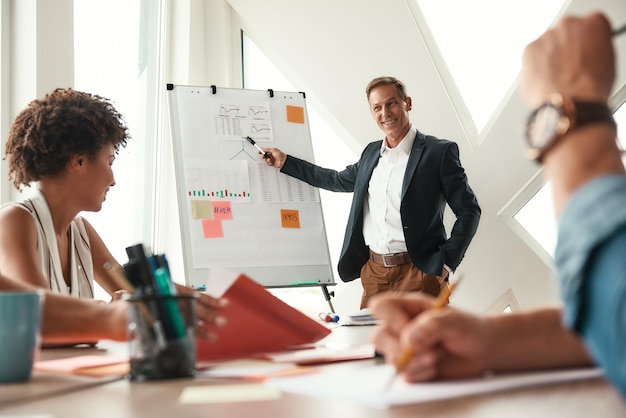 Photo we have great results mature businessman standing near whiteboard and explaining something to his