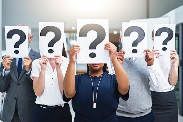 We have some questions Cropped shot of a group of businesspeople holding placards with question marks in front of their faces