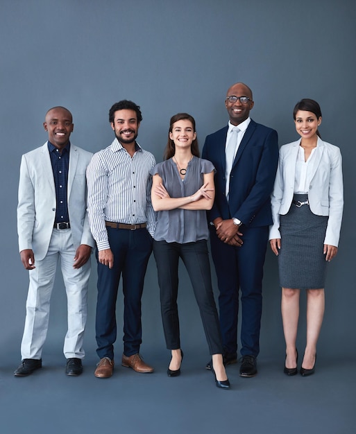 we here for the opportunity studio shot of corporate businesspeople posing against a gray background