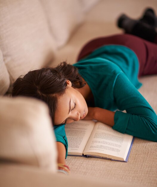 We houden nooit op met genieten van verhaaltjes voor het slapengaan Bijgesneden opname van een jonge vrouw die op de bank een dutje doet met een boek