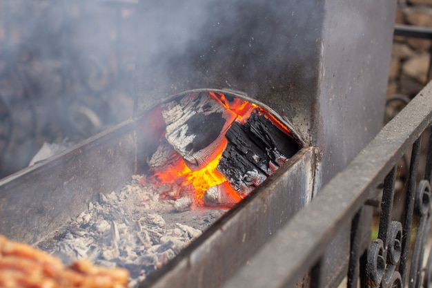 We koken veel kebab op de grill. De brandende kolen. Kebabs aan houten spiesen in een straatcafé. Het proces van het koken van kebab met veel rook.