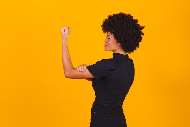 We kunnen het. Vrouwenvuist van vrouwelijke kracht. Vrouw slachtoffer van racisme. Misbruik op het werk. De vrouwelijke kracht. Vrouwelijke empowerment. De kracht van vrouwen. Gele achtergrond.