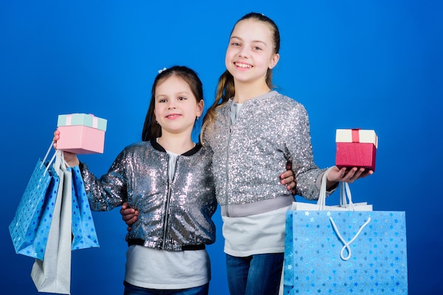 We love shopping Small girls with shopping bags Sisterhood Holiday purchases Kid fashion shop assistant with package Sales and discounts Happy children Little girl sisters with gift box