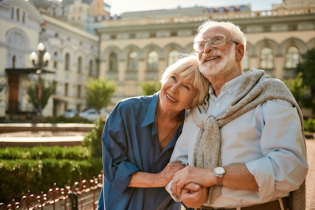 We love to travel together happy senior couple bonding to each other and smiling while standing