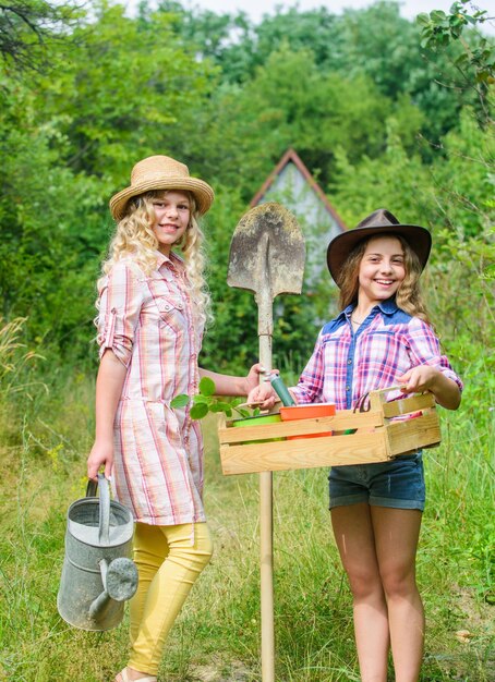 私たちは植物の仕事が大好きです子供たちはガーデニングツールを保持しています村の小さな女の子農家アースデイ夏の農場農業と農業春の田舎の生態学と環境保護