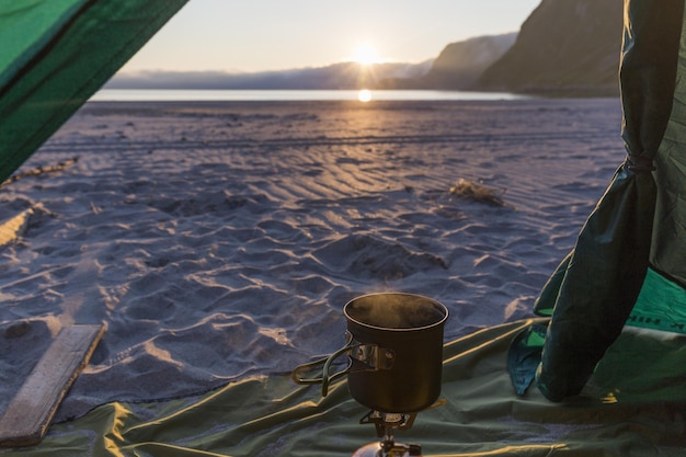 Foto facciamo il caffè su una stufa nella tenda mentre guardiamo il tramonto sul mare.