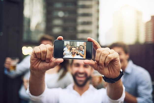 We moeten samen op de foto Portret van een groep vrolijke jonge collega's die overdag samen buiten een zelfportret maken