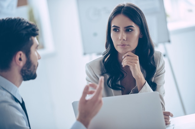 We need to make important decision! Two coworkers discussing something while sitting at the office table