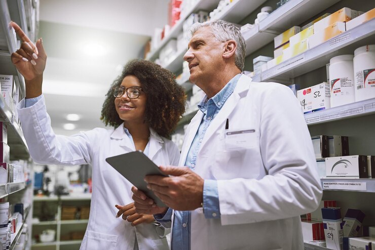 Photo we need more of this meds shot of two focused pharmacist walking around and doing stock inside of a pharmacy