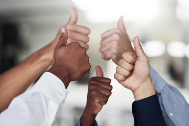 We say yes to success Shot of a group of unidentifiable businesspeople showing thumbs up in the office