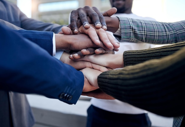 We support each other. Shot of a group of unrecognizable businesspeople stacking their hands outside.