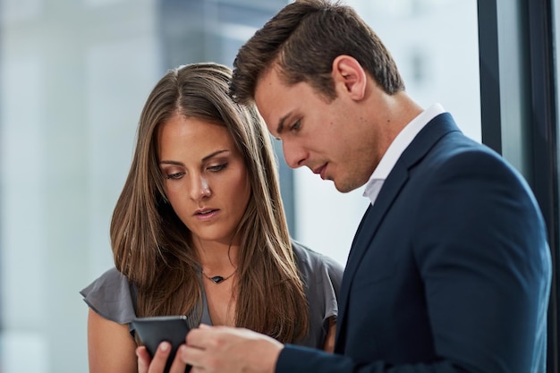 We take our online presence serious Cropped shot of two businesspeople looking at something on a cellphone