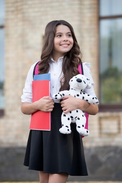 Foto ti insegniamo a imparare. bambino felice tenere giocattolo e libri all'aperto. ritorno all'essenziale per la scuola. istruzione elementare. doposcuola e scuola materna. giochi educativi. uniforme scolastica. impara e gioca oggi.