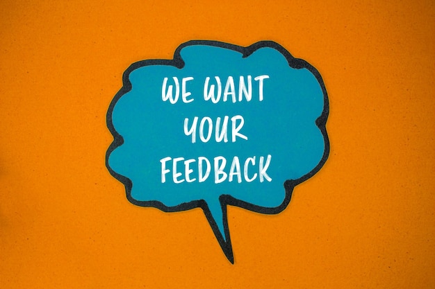 We want your feedback message written on blue paper speech bubble with orange background Conceptual we want your feedback symbol Copy space