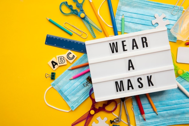 Wear a mask lightbox message with school equipment and covid masks