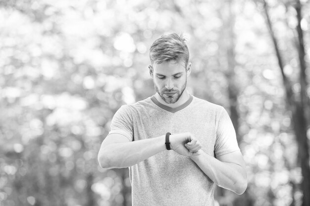 Wearable technology Handsome athlete using smartwatch technology during training outdoor Fit athlete tracking his performance with sports watch technology Technology makes sport training smarter