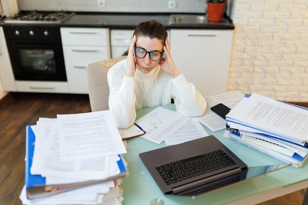 Foto indossando gli occhiali una donna prende una pausa molto necessaria dal suo lavoro a casa il suo laptop e vari