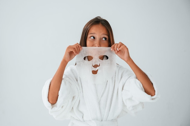 Foto indossare una maschera per il viso concezione della bellezza e della cura di sé la giovane ragazza è nello studio