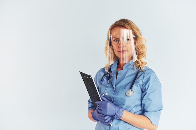 Wearing protective mask Young female doctor in uniform is indoors