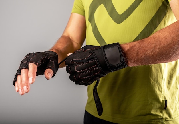 Wearing putting on sport workout gloves close up for palm and\
wrist protection in gym