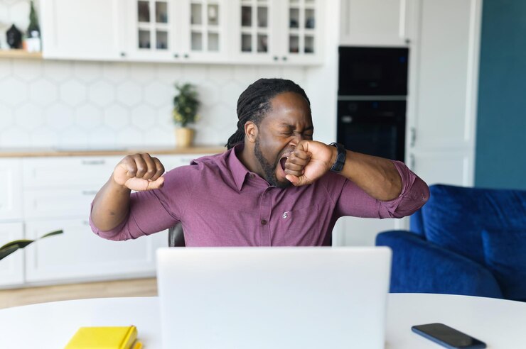 Photo weary africanamerican freelancer man sits at the desk and yawning