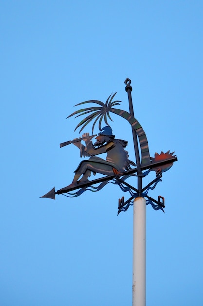 Weather vane against blue sky