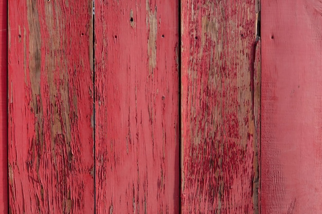 Weathered dark bright scarlet red painted vertical wooden plank wall with painted nails