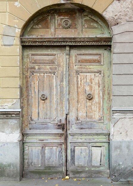 Foto vecchia porta verde deteriorata con serratura in ferro battuto e volta a botte
