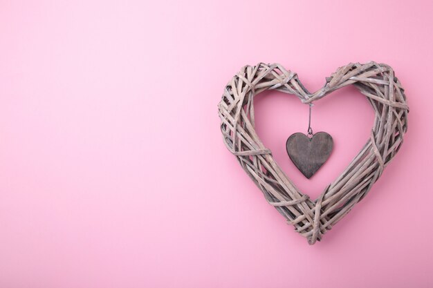 Weaved wooden heart on pink , top view