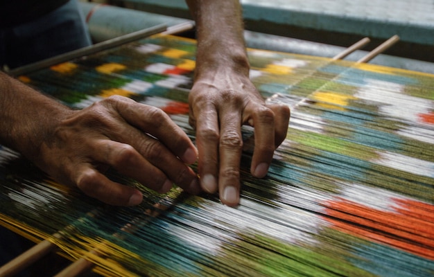 Weaving and manufacturing of handmade carpets closeup. man's hands behind a loom