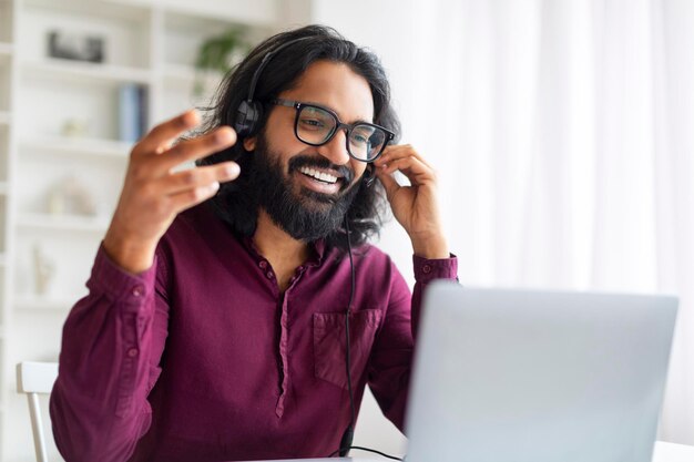 Photo web conference smiling indian man in headset making video call via laptop