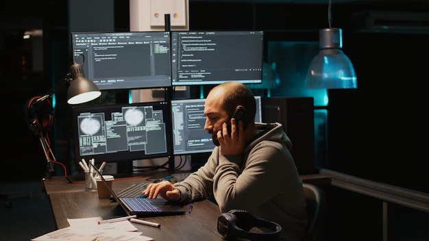 Web developer talking on phone call in programming office,\
using smartphone for remote conversation. male engineer working on\
html code developing, holding mobile phone. handheld shot.