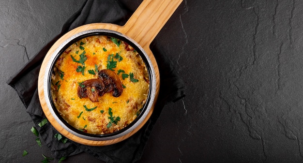 Webbanner julienne met aardappelen en champignons in een ovenschaal op een donkere achtergrond kopieerruimte voor space