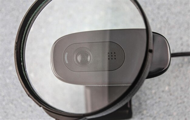 Webcam through a magnifying glass A modern webcam for a personal computer with a microphone for online streaming live broadcasts Webcam peephole