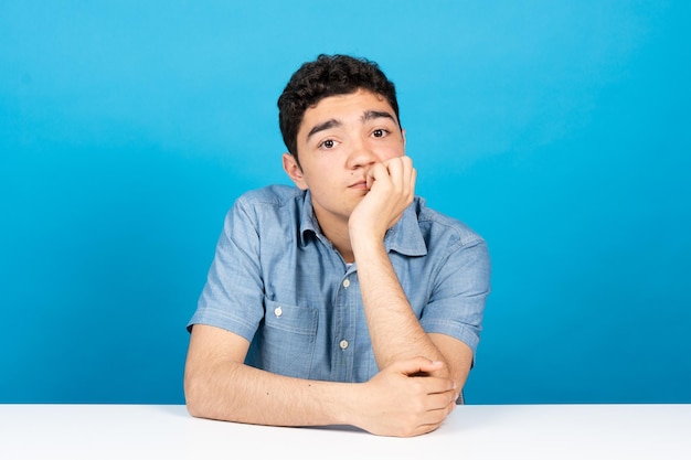 Webcam view of bored hispanic teenager looking at camera isolated on blue background