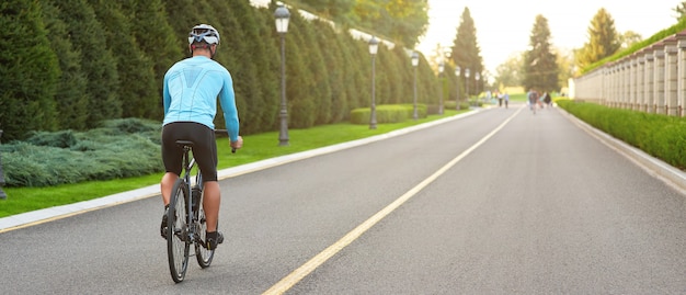 日没時に公園でマウンテンバイクに乗っている男性のトリミングされたショットのウェブサイトのヘッダー