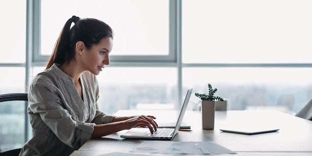 Photo website header of portrait of gorgeous smiling young female using laptop computer at workplace side