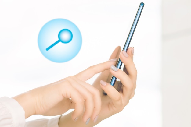 Поиск по сайту на телефоне, женские руки со смартфоном и значком увеличительного стекла