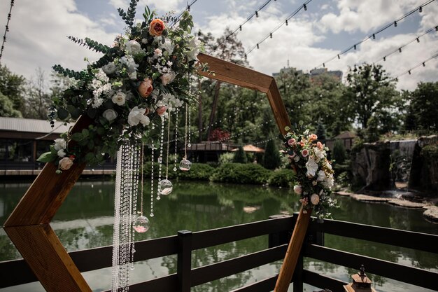 Wedding arch decor with crystals and flowers in the park near the water closeup for the holiday