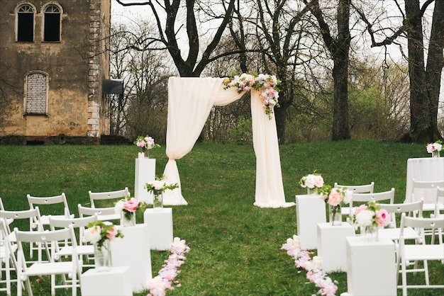 Wedding arch decorated with cloth and flowers outdoors Beautiful wedding set up Wedding ceremony on green lawn in the garden Part of the festive decor floral arrangement