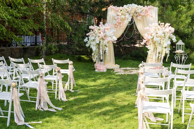 Wedding arch decorated with cloth and flowers outdoors.