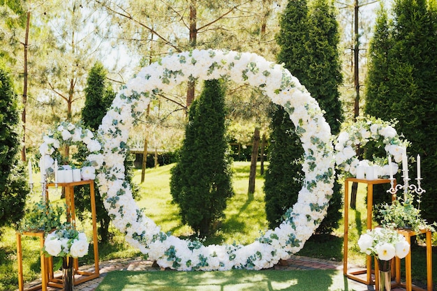 Arco nuziale decorato con fiori bianchi freschi e vegetazione