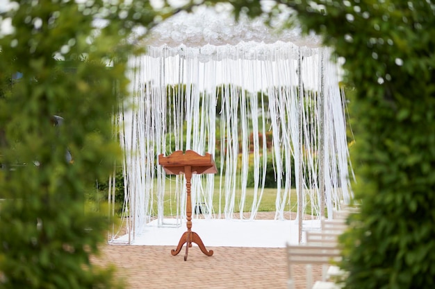 wedding arch of the newlywedsand a wooden stand for the priest white sparkling threads and flowers