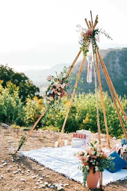 Wedding archwigwam with a blanket and flowers stands high in the mountains