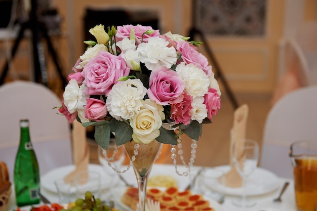 wedding arrangement in a tall glass in white and pink tones composed of carnations and roses wedding decoration