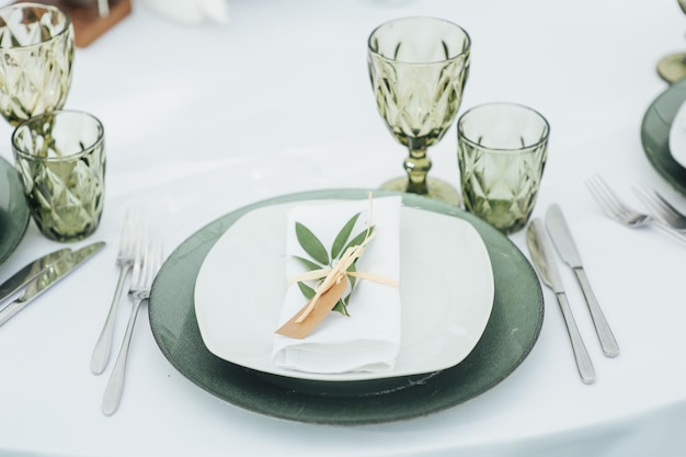 Wedding Banquet The chairs and round table for guests served with cutlery greenery flowers and crockery and covered with a white tablecloth olive color