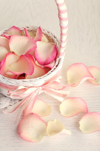 Wedding basket with roses petals on table, on light background