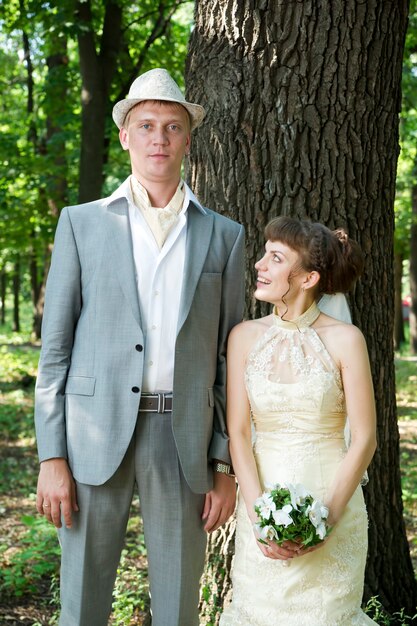 Foto matrimonio bella giovane sposa e sposo in piedi in un parco