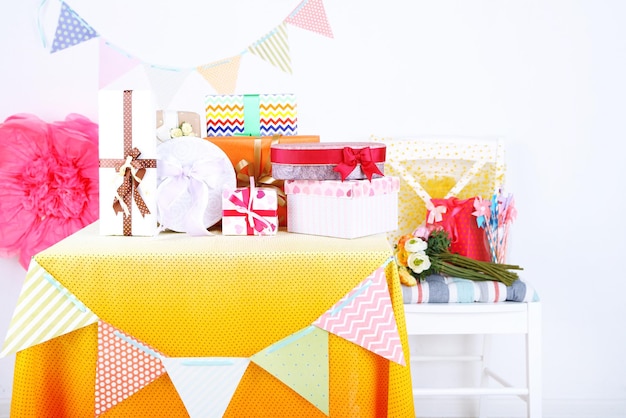 Wedding or birthday gifts on decorated table, on bright background