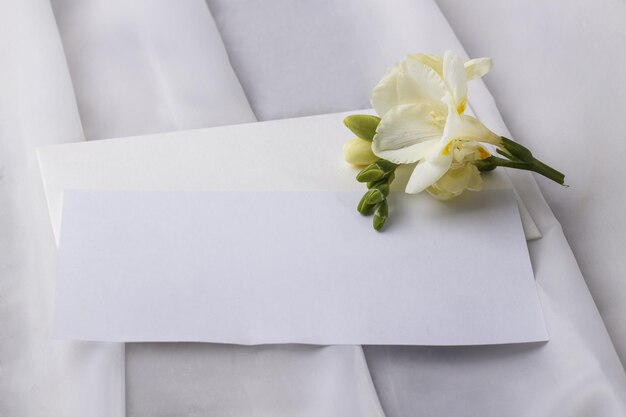 Photo wedding blank and an envelope with a delicate freesia flower on a light table